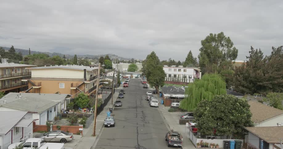 Aerial shot of a city street lined with cars, where shoes hang from a wire