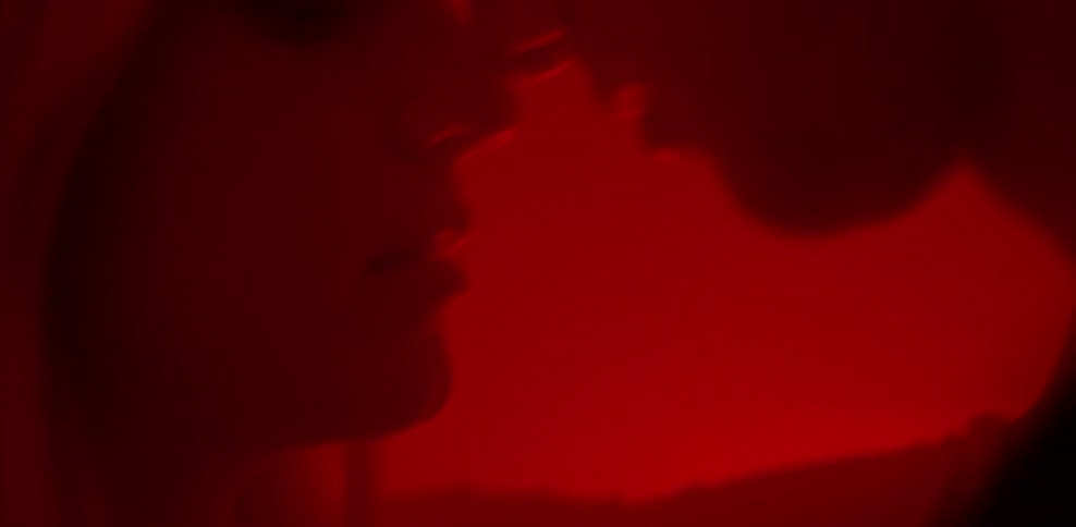 A man and woman embrace in a red room