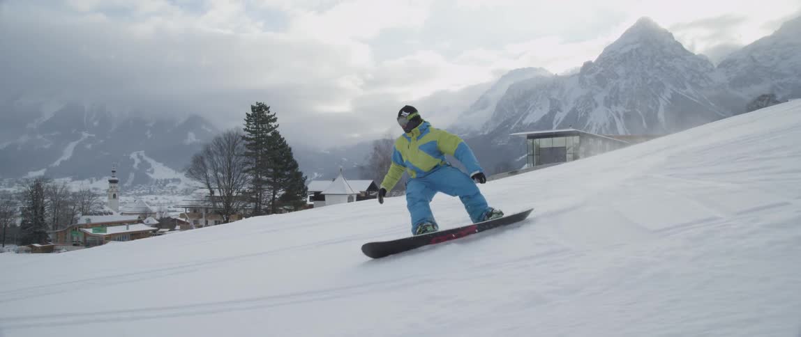 A snowboarder rides down a mountain slope and comes to a stop