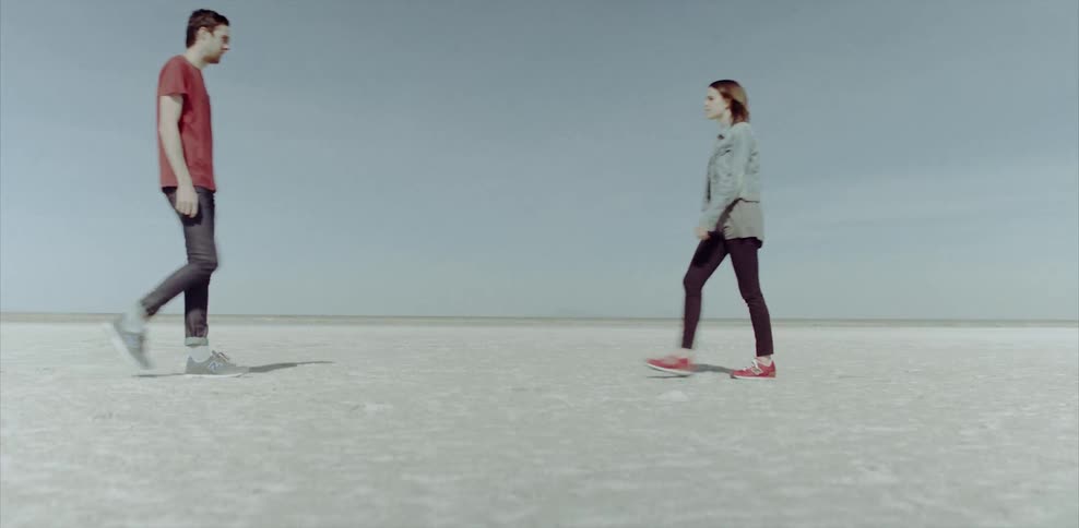 A man and woman walk toward and face each other outside