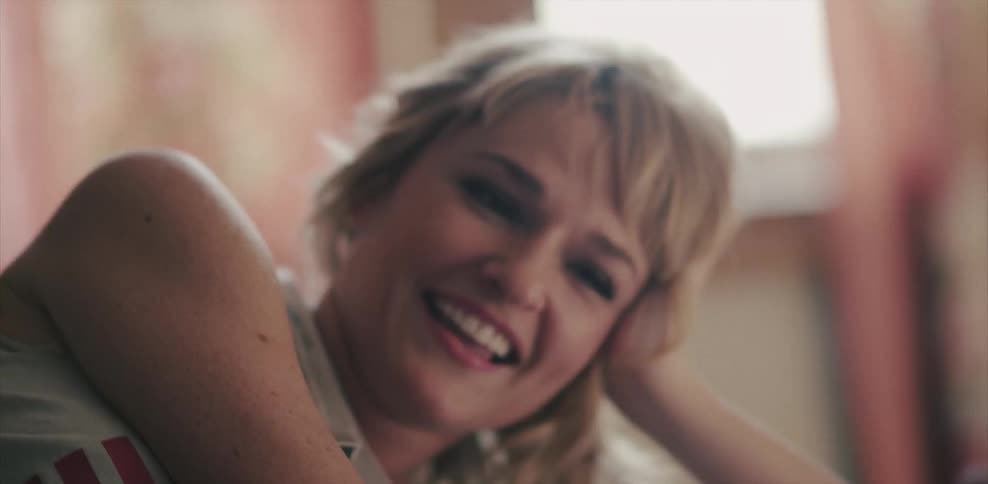 Two women lie on a bed talking and laughing during the day