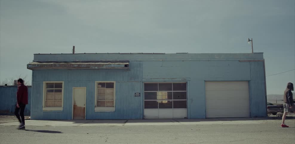 Man and woman walking away from each other in front of a blue building