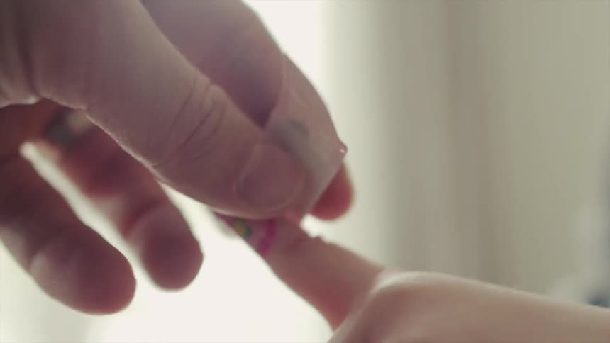 An adult helps a child put a bandaid on a finger that doesn't have a wound