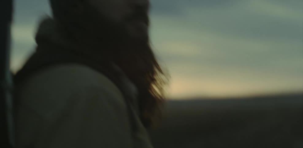 A bearded man wearing a backpack turns around