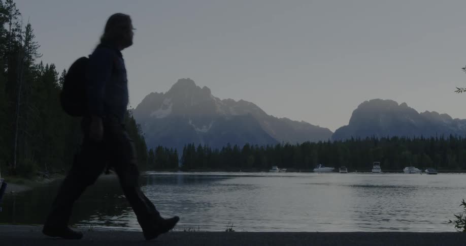 Man walks by a tree lined lake