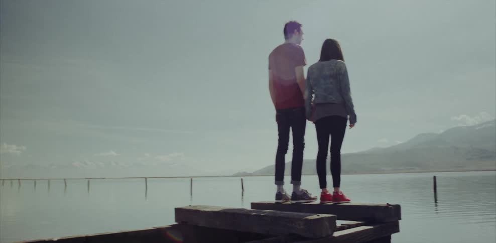 A man and woman walk to the end of a broken dock