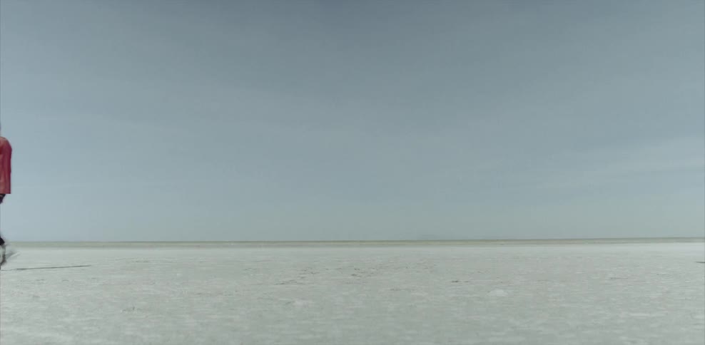 A man and woman walk away from each other on a salt flat
