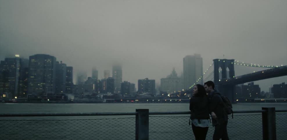 Man and woman stand in front of a river overlooking at city