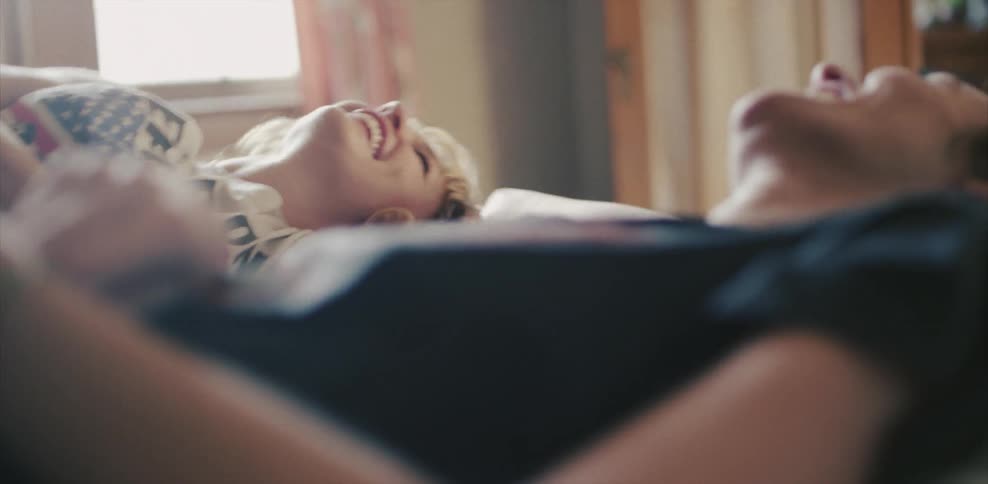Two women smile and lay in bed talking