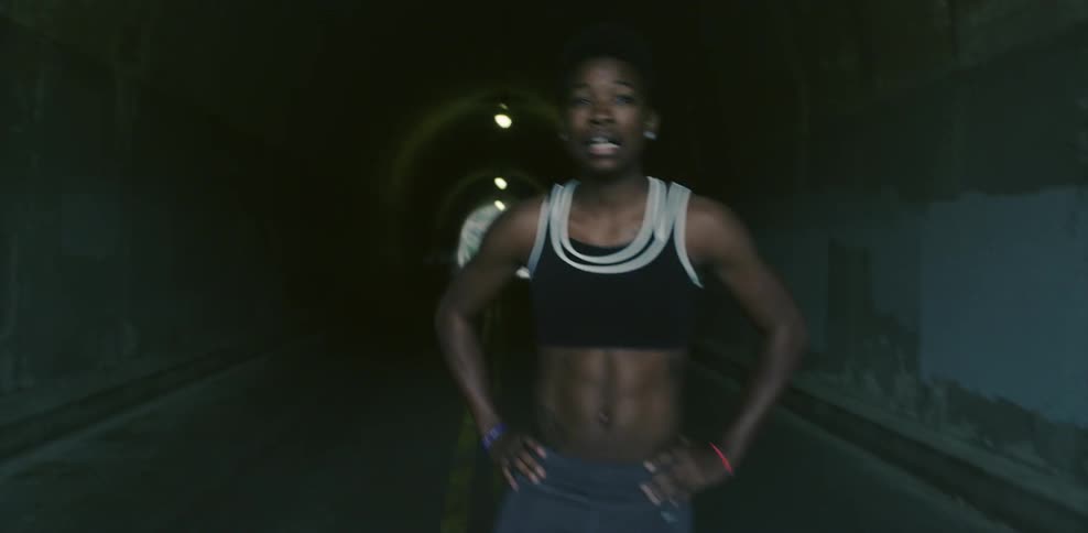 A female jogger stops to catch her breath in the roadway in a tunnel
