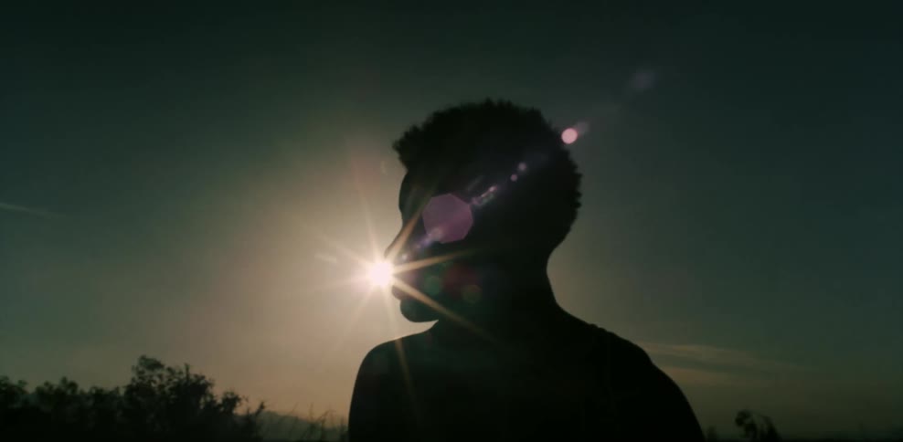 Woman looks out at hills and the sun