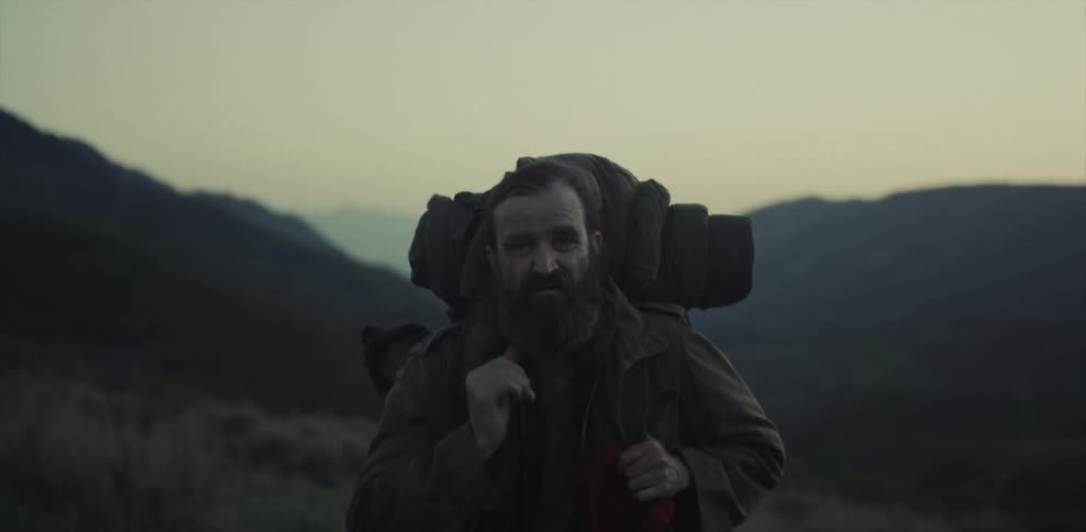 A man hiking outside takes his hat off