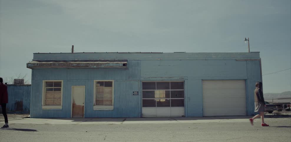 Man and woman walking away from each other in front of a blue building