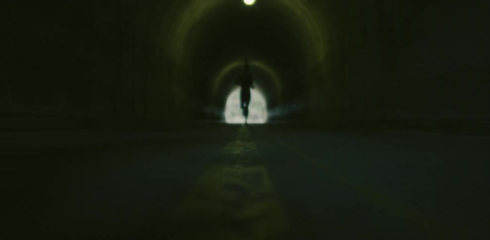 View of a tunnel lit by dim lights as a person runs through it
