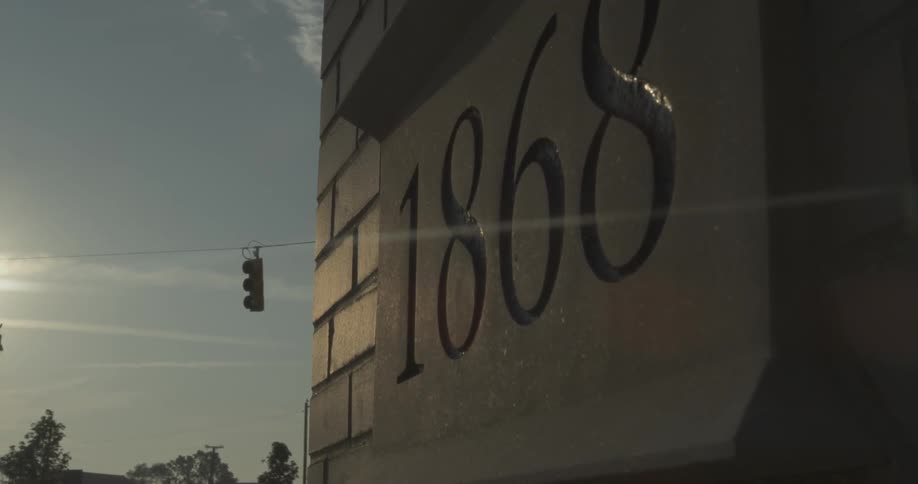 The sun casts rays onto a stone sign on a brick building