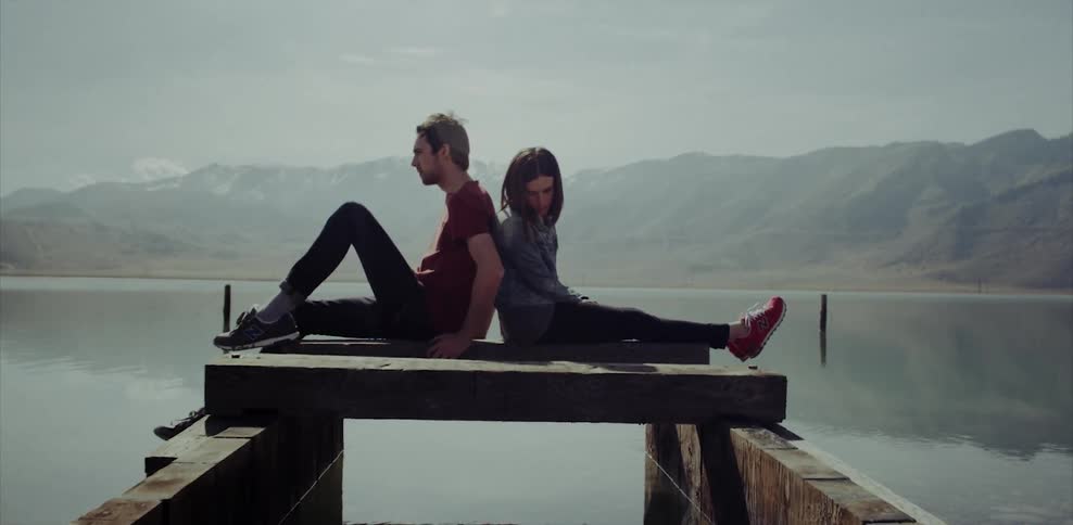 Man and woman sitting back to back looking out at water
