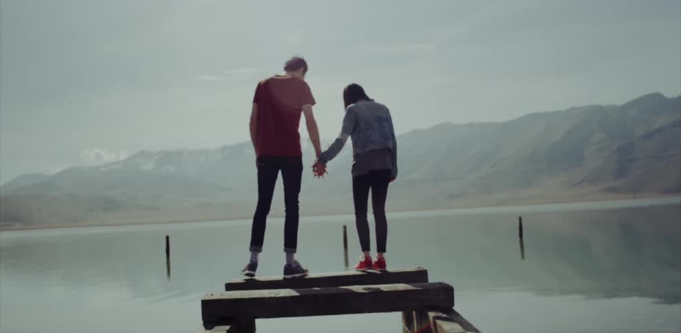 A man and a woman holding hands on a broken dock