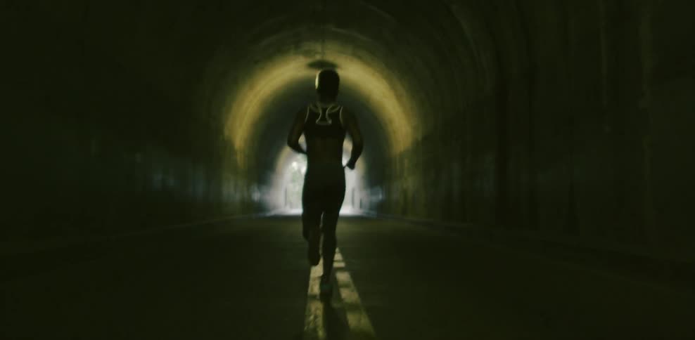 Woman jogs through a tunnel on a sunny day