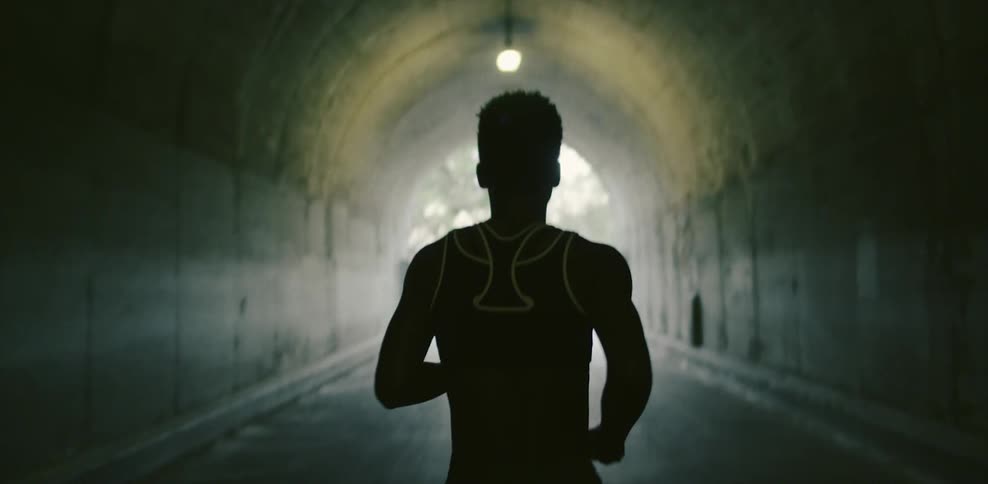 Woman jogs through a tunnel on a sunny day