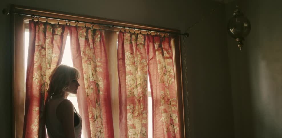 Woman standing next to a window that's covered with colorful curtains