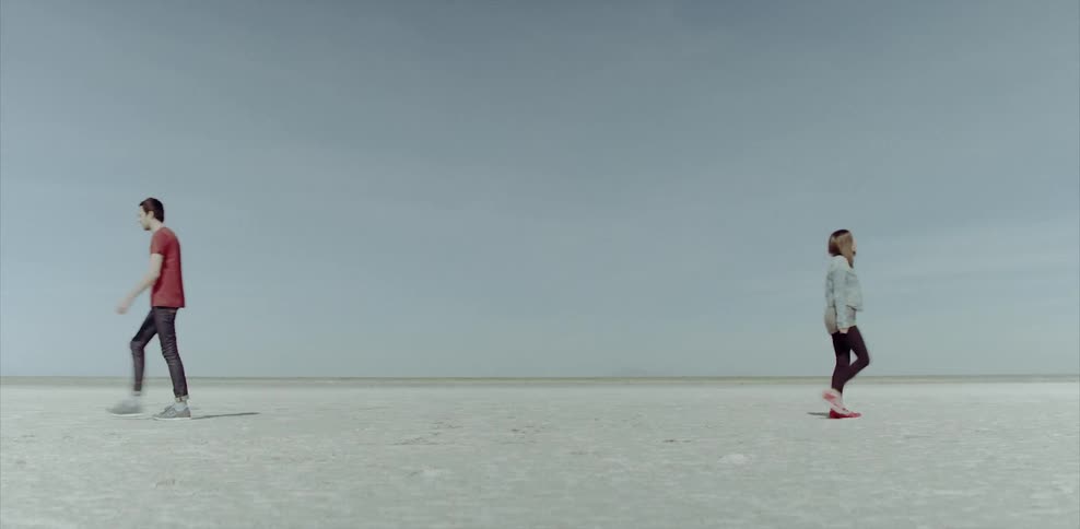 Man and woman standing in the desert walk away from each other