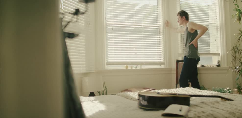 Man looks out of a window in a bedroom