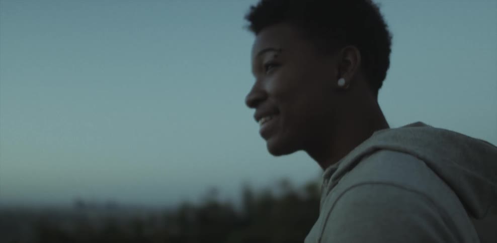 A man smiles while looking out over a valley at dusk