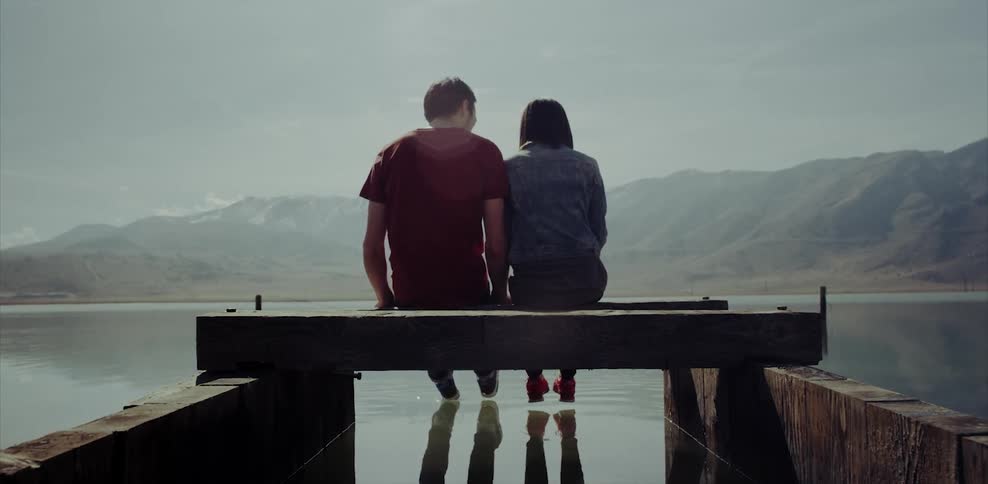 Man and woman sitting on a dock putting their feet in the water