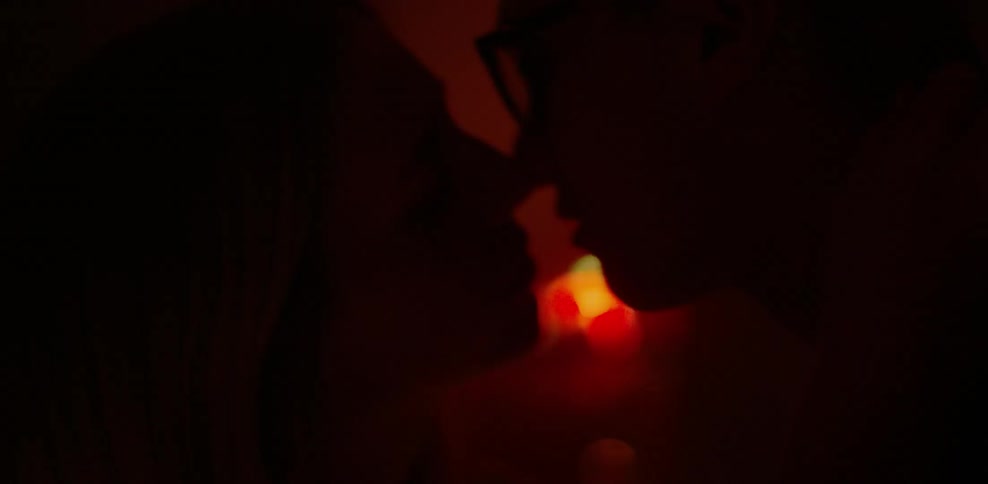 A couple kiss in a red lit room