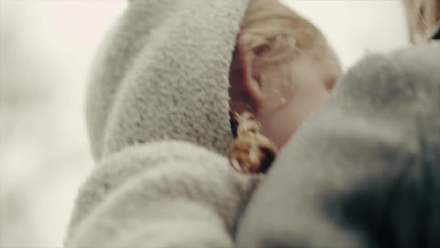 A mother holds her child in the snow