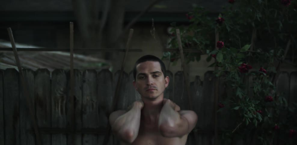 Man stands in front of a wooden fence