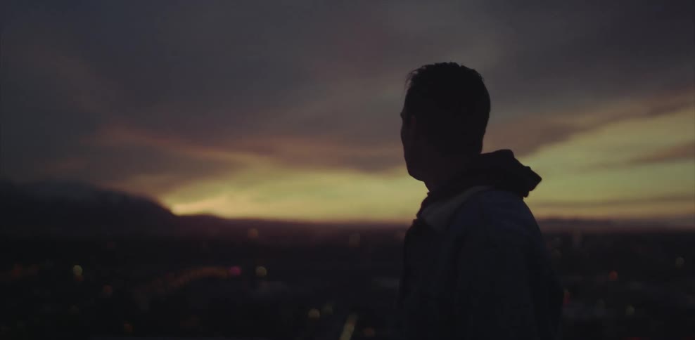Man looking towards a cloudy horizon at sunset