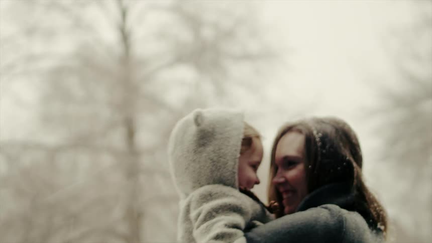 A woman holds a young girl in the snow