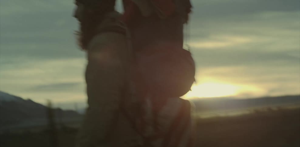 Man wearing a backpack walks through the country at sunset