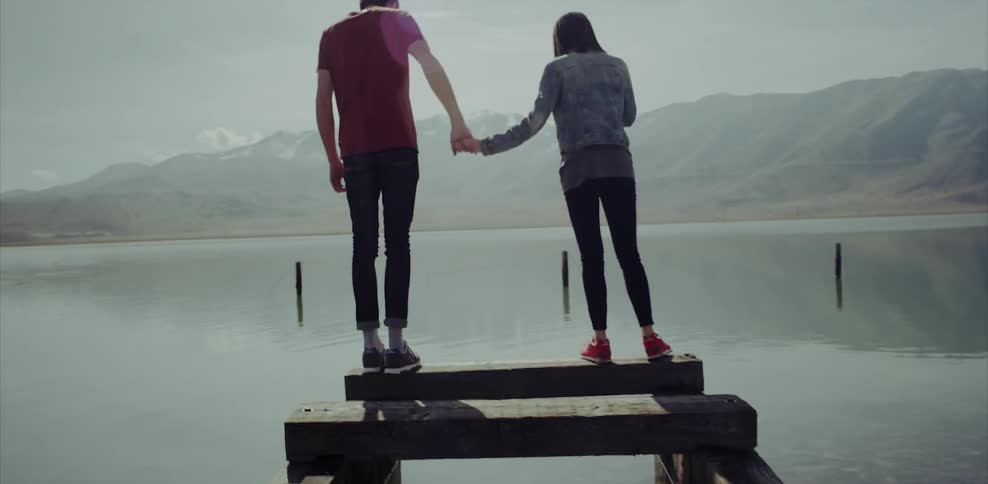 Man and woman hold hands walking on a dock