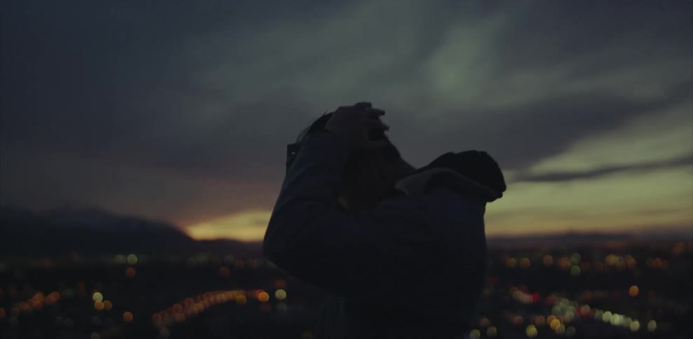 Silhouette of a man looking down on a city at night