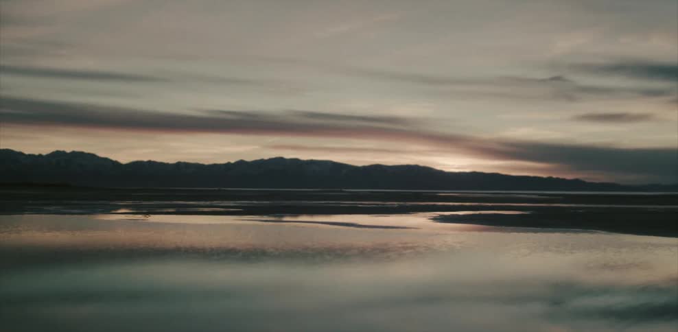 A lake with mountains in the background at dusk