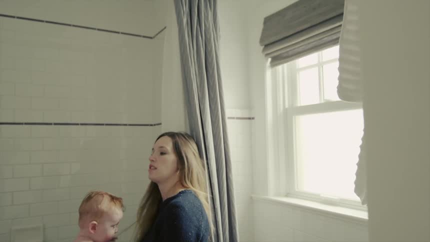 A mother bounces her baby as she holds him and dries him with a towel