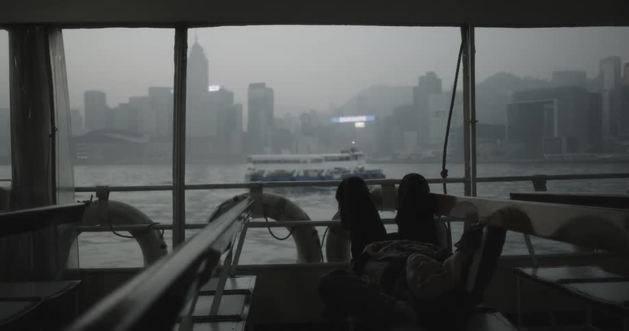 A man rides a ferry boat on an overcast day