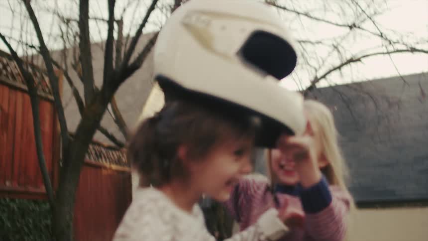 Two girls play outdoors with a helmet