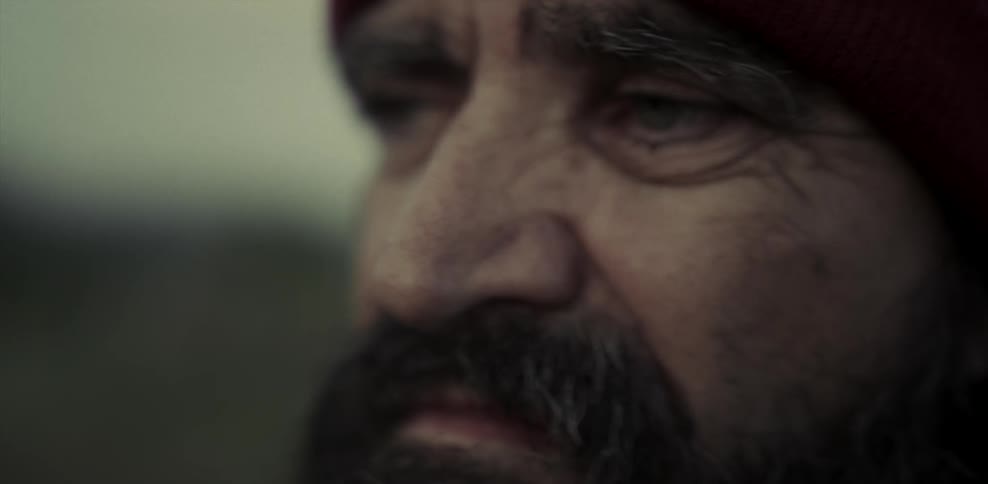 An older man with a beard looks around