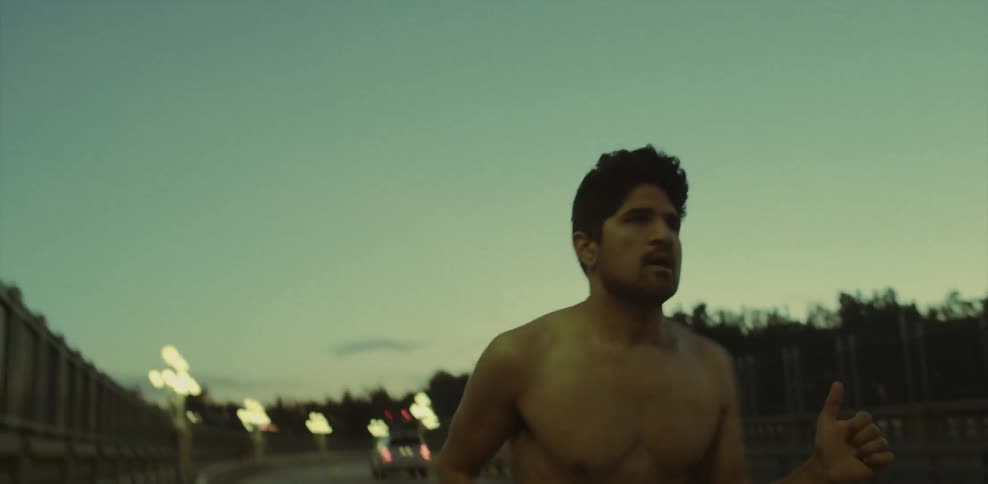 A man is jogging on a parkway at dusk