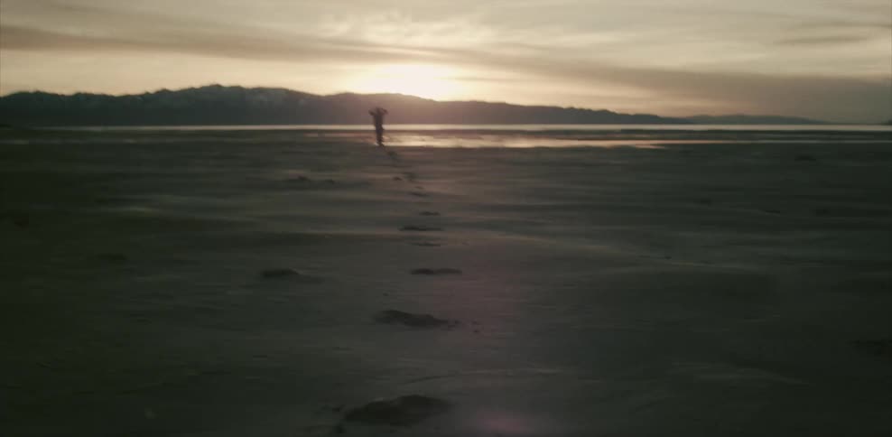 A person jogging on the beach waves their arms