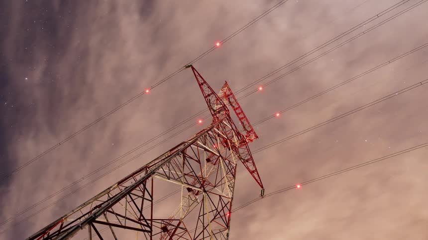 Clouds rolling over power lines and tower at night