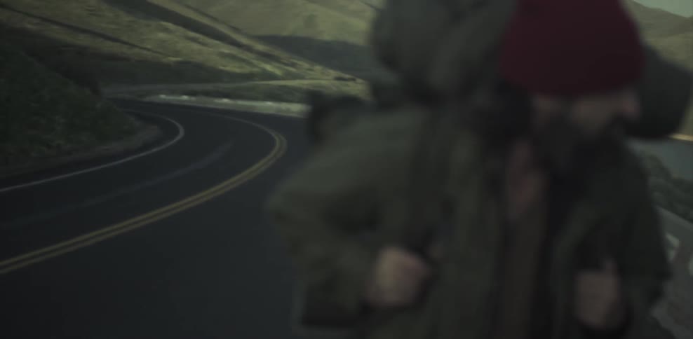 Man wearing a backpack walks alongside a country road