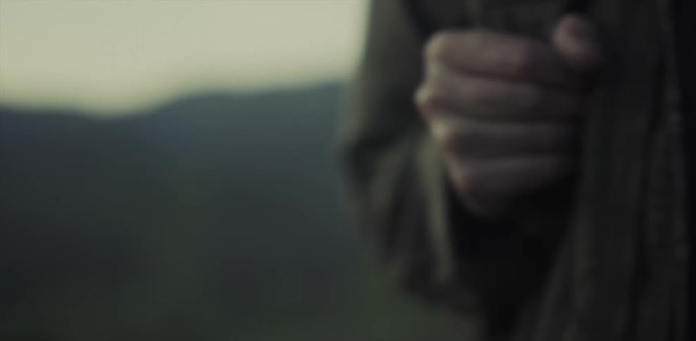 A man stands in the wilderness with a backpack at sunset
