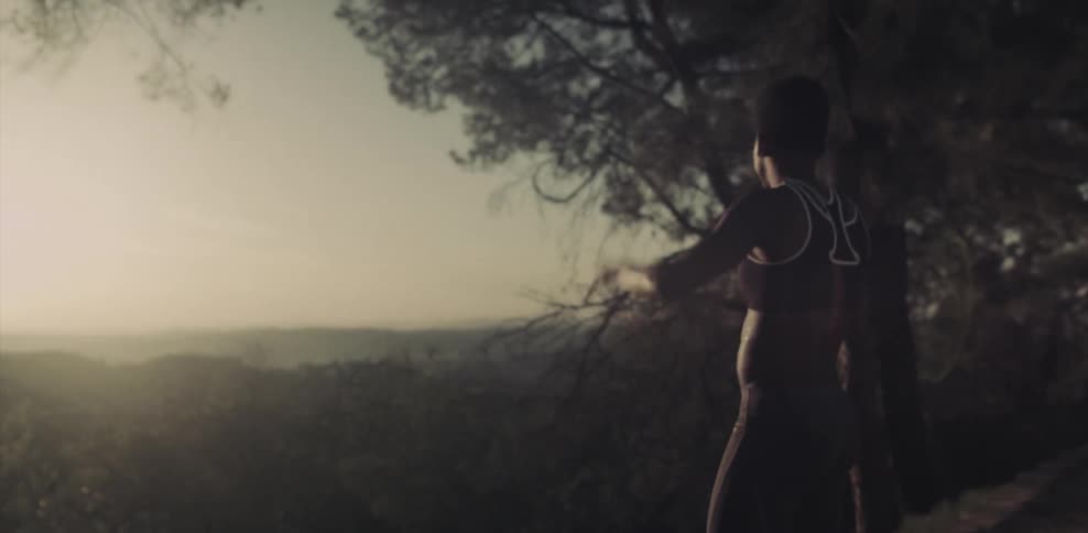 Woman looks out at hills and the sun