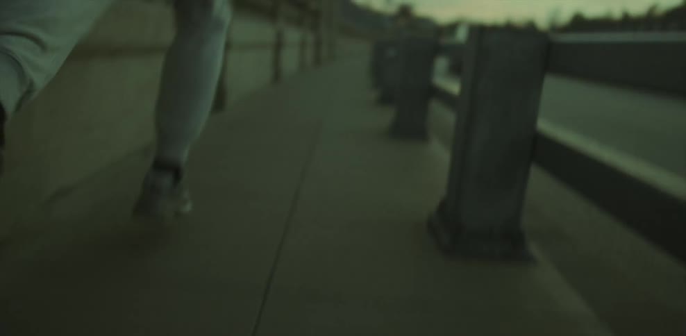 A jogging man hops over the railing onto the sidewalk