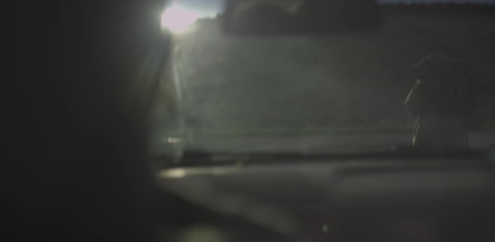 A person driving a car passes a man hiking along the side of the road