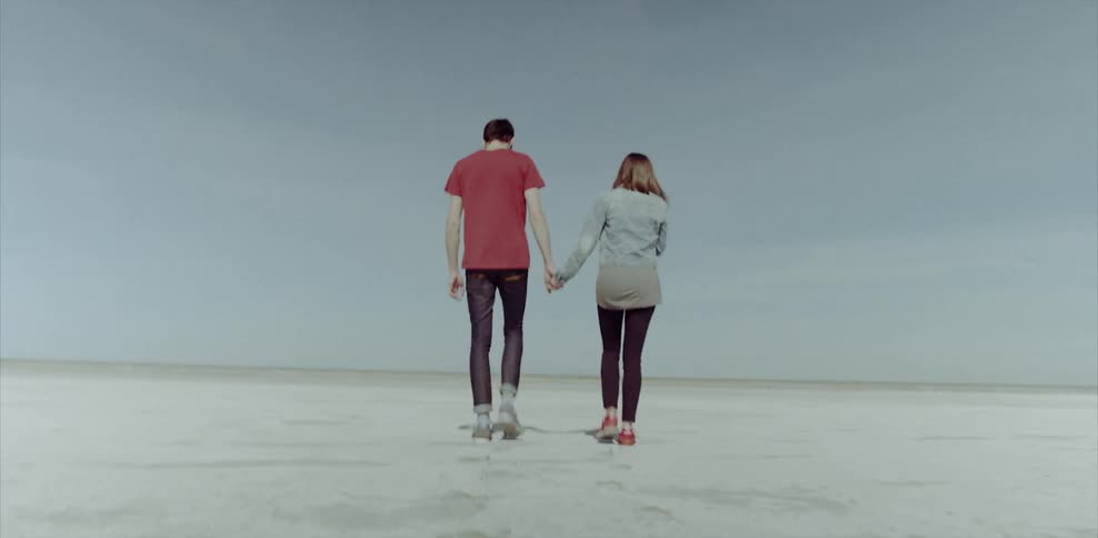 Man and woman hold hands and walk through desert